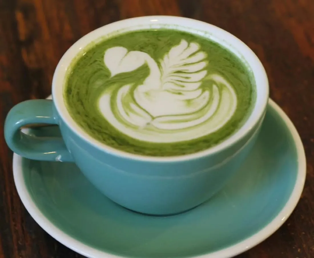 Matcha latte with swan latte art in a teal cup
